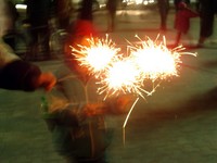 Xiao Yang's son Julian holds three sparklers at the Lantern Festival in the Railway District's main square.