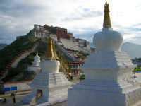 The Potala Palace at sunrise, with three white stupas in the foreground.