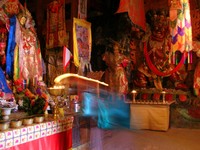 A pilgrim adds yak butter to a devotional lamp at the King of Gesar Temple.