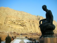 The Kizil Thousand Buddha Caves from afar, with a statue of the guy who founded the caves' monastery in the foreground. (I forget his name, and my guidebook is not at my side.)