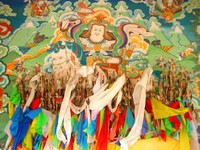 Beautiful wall painting behind a display of arrows and prayer flags. 