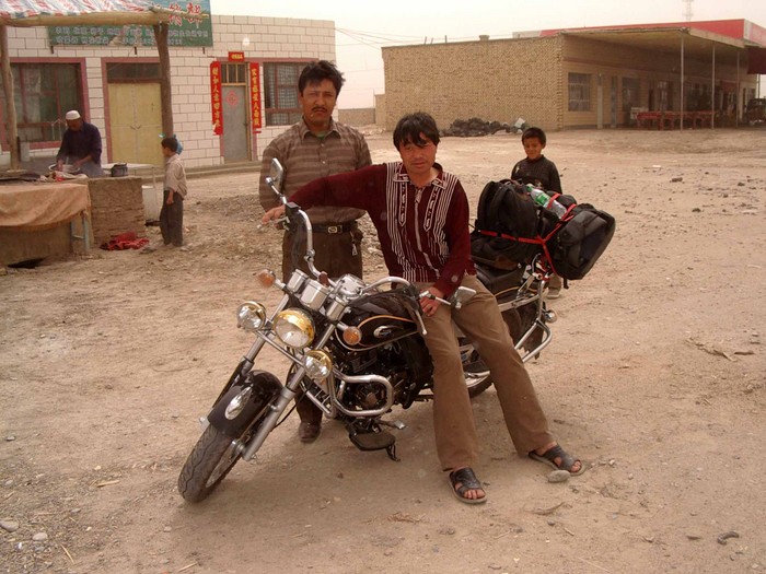 The last small town before the Taklamakan. I stopped to eat a nan bread while these Uyghurs checked out my motorcycle.