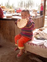 I stopped on the way to Hotan (Hetian) to grab a snack, and snapped this photo of a little Uyghur girl enjoying a nan bread.